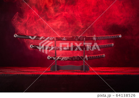 Three swords on stand, red smoke behind Three swords on stand, red smoke behind 64138526