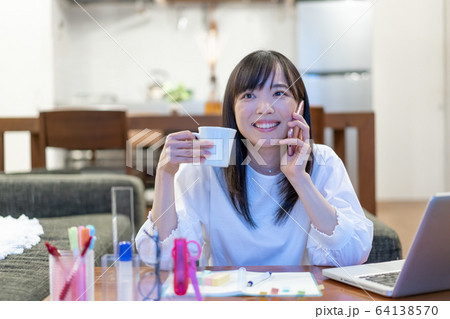 夜リビングでスマホで話をすながらお茶を飲む若い女性 夜リビングでスマホで話をすながらお茶を飲む若い女性 64138570