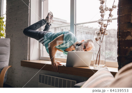Young man doing yoga at home while being quarantine and freelance working 64139553