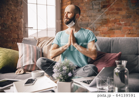 Young man doing yoga at home while being quarantine and freelance working 64139591