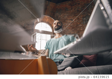 Young man doing yoga at home while being quarantine and freelance working 64139615