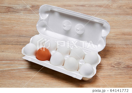 egg crate with nine white eggs and one brown on a 64141772