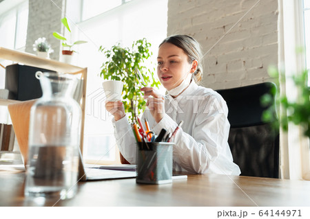 Woman working in office alone during coronavirus or COVID-19 quarantine, wearing face mask Woman working in office alone during coronavirus or COVID-19 quarantine, wearing face mask 64144971