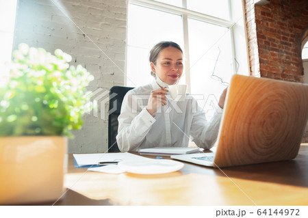 Woman working in office alone during coronavirus or COVID-19 quarantine, wearing face mask Woman working in office alone during coronavirus or COVID-19 quarantine, wearing face mask 64144972