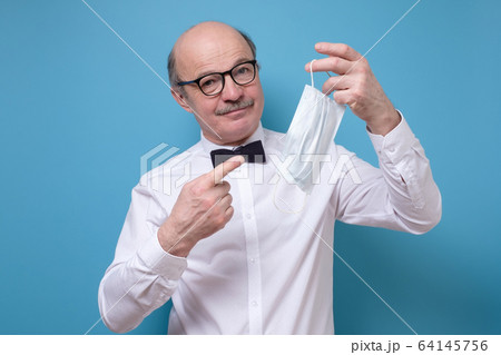 Young caucasian man with mustache pointing on a medical mask. Young caucasian man with mustache pointing on a medical mask. 64145756