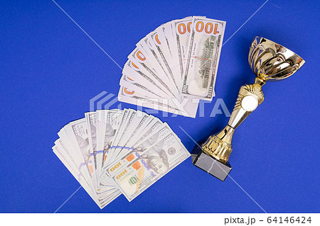 heap of money and winner cup on pure blue table background heap of money and winner cup on pure blue table background 64146424