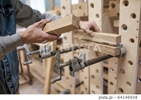 Man gluing furniture details in the carpentry workspace. Man gluing furniture details in the carpentry workspace. 64146938