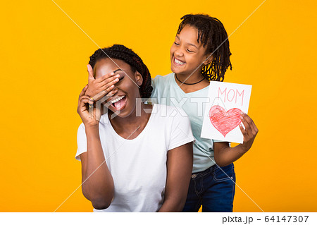 Black girl congratulating her mom isolated at yellow studio 64147307