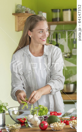 Attractive woman cooking fresh vitamin salad in the kitchen 64147352