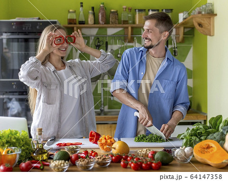 Funny young couple playing with vegetables together 64147358