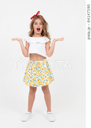 surprised teenager girl in a white t-shirt and skirt is standing in full growth on a white 64147590