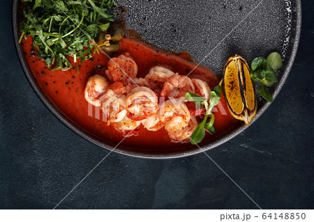 Grilled tiger crackers beautifully canned on a plate with tomato sauce and arugula, Mediterranean food concept, Food photo. Top view, blue background, copy space 64148850