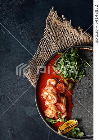 Grilled tiger crackers beautifully canned on a plate with tomato sauce and arugula, Mediterranean food concept, Food photo. Top view, blue background, copy space 64148852