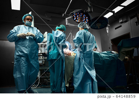 Surgical team operating on patient in theater in hospital Surgical team operating on patient in theater in hospital 64148859