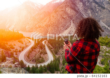 Adventurous Girl Taking Pictures of a Scenic Road in the Canadian Mountain Landscape Adventurous Girl Taking Pictures of a Scenic Road in the Canadian Mountain Landscape 64152163