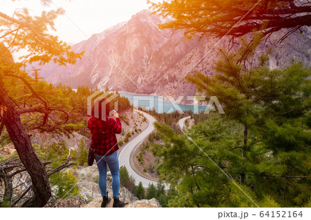 Adventurous Girl Taking Pictures of a Scenic Road in the Canadian Mountain Landscape Adventurous Girl Taking Pictures of a Scenic Road in the Canadian Mountain Landscape 64152164