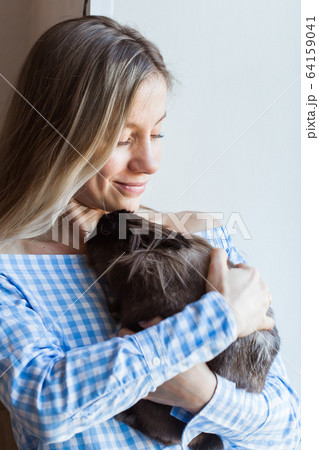 Pet and Easter concept - Happy girl hugging brown rabbit at home. Pet and Easter concept - Happy girl hugging brown rabbit at home. 64159041