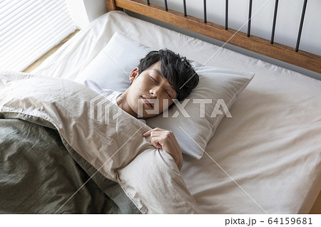 ベッドで眠る若い男性 64159681