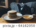 Pancakes with honey on wooden tray in cozy room. 64162050