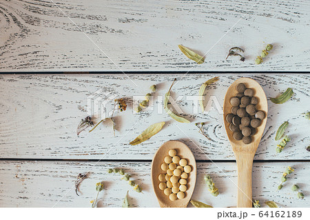 Herbal pills and dry herbs on wooden background. Herbal pills and dry herbs on wooden background. 64162189