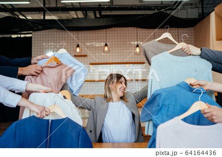 Young stylist looking through set of shirts for fashion shooting 64164436
