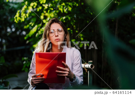 Young female agricultural engineer working in greenhouse. Young female agricultural engineer working in greenhouse. 64165114