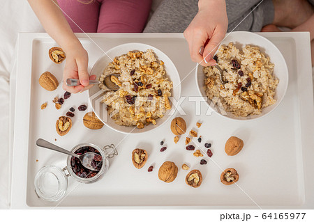 Happy mom and daughter have healthy breakfast on bed in a light bedroom on a sunny morning. Oatmeal 64165977