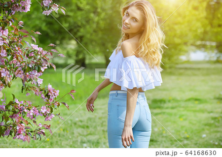 Beautiful young woman walking near the blossoming Beautiful young woman walking near the blossoming 64168630