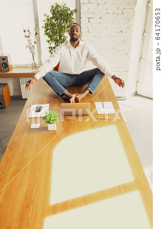 Young african-american man doing yoga at home while being quarantine and freelance working Young african-american man doing yoga at home while being quarantine and freelance working 64170653