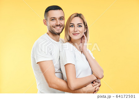 Young happy couple hugging over yellow background Young happy couple hugging over yellow background 64172501