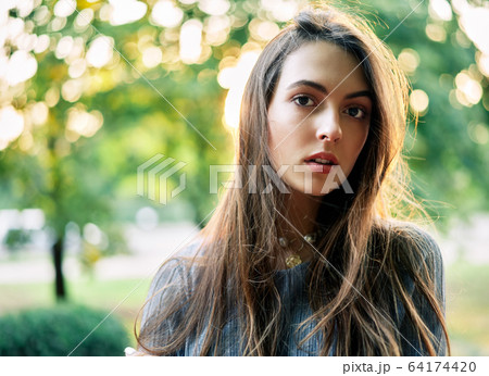 Young beautiful woman outdoors on green background summer nature 64174420