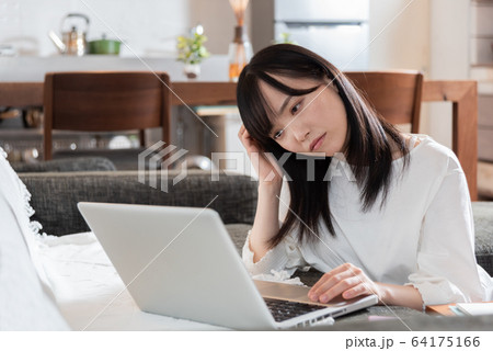 リビングで考え込む若い女性 64175166