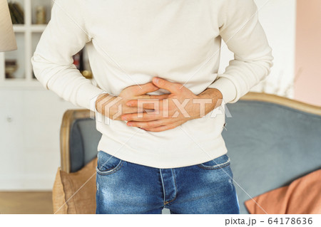Young man suffering from an abdominal pain Young man suffering from an abdominal pain 64178636