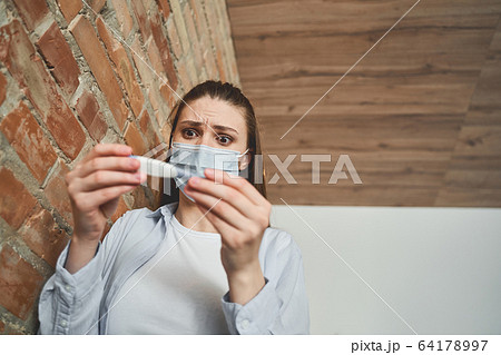 Ill female in a mask standing at the wall Ill female in a mask standing at the wall 64178997