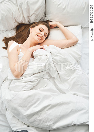 Girl with loose long hair lying in bed 64179224