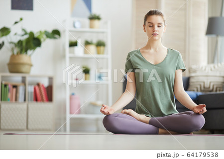 Woman meditating at home Woman meditating at home 64179538
