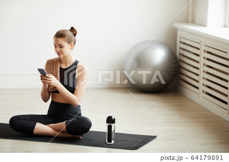 Fit woman using her phone Fit woman using her phone 64179891