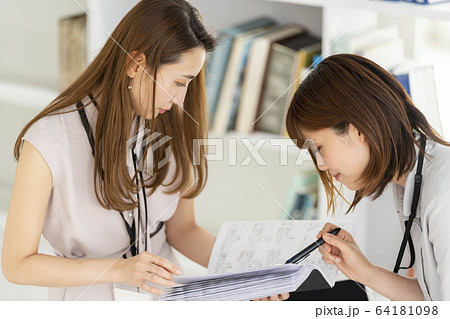 図面を見ながら打ち合わせをする女性二人　ビジネスシーン 64181098