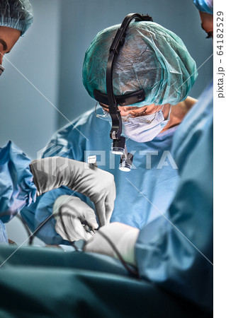 In the hospital operating room. An international team of professional surgeons and assistants works in a modern operating room. Professional doctors celebrate successfully saved lives. 64182529