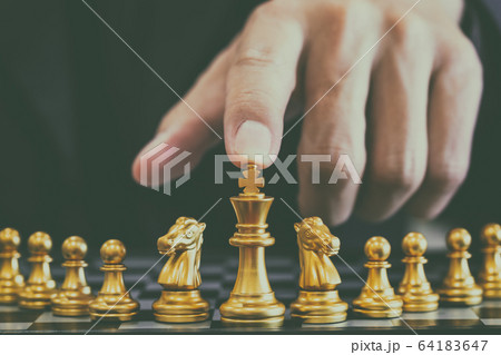 Chess game on chess board behind business man 64183647