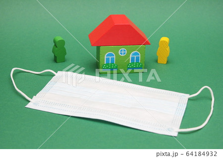 Medical mask near wooden figures of a house and a 64184932