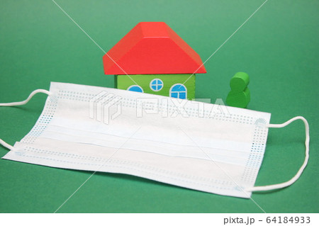 Medical mask near wooden figures of a house and a 64184933