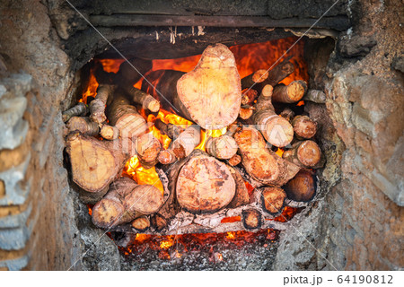 Burning fireplace with piece of firewood burning 64190812