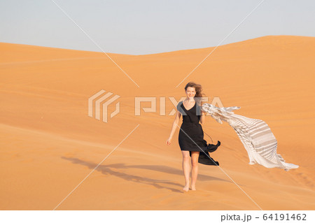 A girl walks on the sand in a deserted desert. 64191462