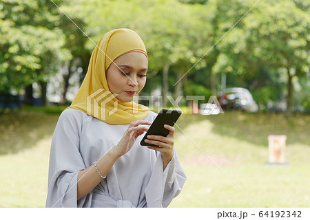 Muslim girl using smart phone Muslim girl using smart phone 64192342