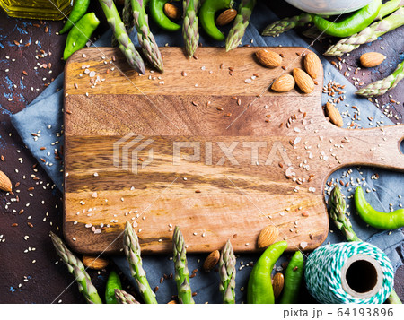 Wooden chopping board with asparagus, nuts, salt 64193896