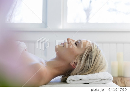 Woman lying on back on massage table with eyes closed Woman lying on back on massage table with eyes closed 64194790