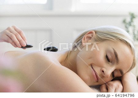 Woman receiving hot stone treatment at spa 64194796