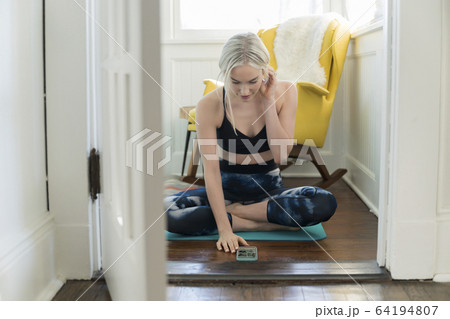 Woman working out at home with live stream on phone 64194807