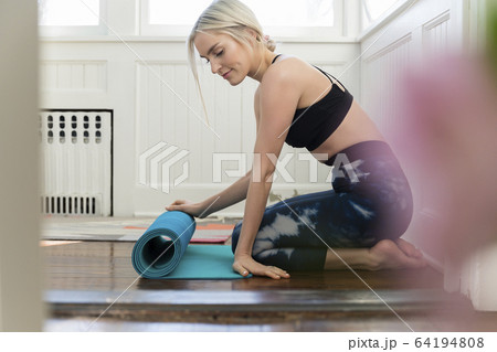 Young woman unrolling yoga mat at home Young woman unrolling yoga mat at home 64194808